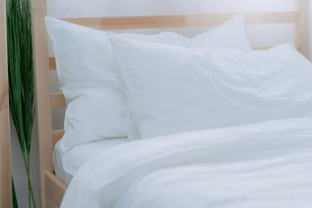 Bed freshly made with crisp white hotel-style linens in a bright short-term rental bedroom